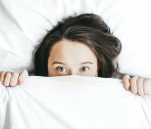 Is L-Theanine Good for Social Anxiety - Woman Hiding Under Bed Sheet